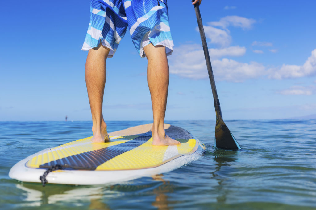 Young Attractive Mann on Stand Up Paddle Board, SUP, in the Blue Waters off Hawaii